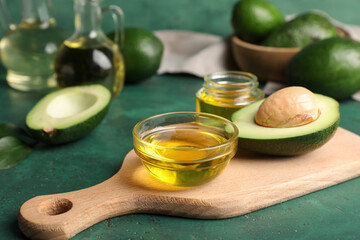 Bowl and jar of avocado oil on green background