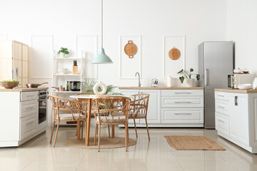 Interior of light kitchen with white counters, shelf unit and dining table
