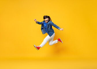 Obraz premium Beautiful female skater jumping on orange background