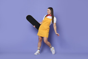 Smiling woman with skateboard on violet background