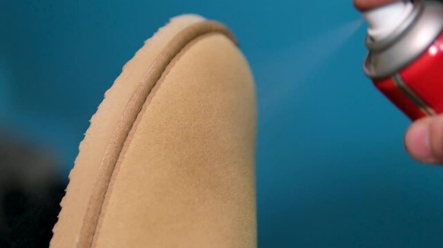 beige ugg boots Applying a water-repellent hydrophobic spray to white women's sneakers. Protection of shoes from moisture, dirt and unpleasant odor.