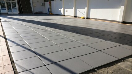 The play of shadows across the expansive sheet of underlayment emphasizing the smoothness and flatness required to support perfectly aligned tile.