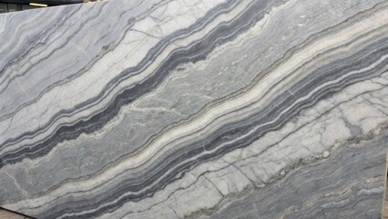 Detailed image of a gray marble slab marked by contrasting dark and light bands forming an eyecatching pattern resembling abstract art highlighting the natural beauty of the stone.