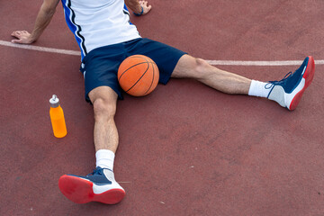 Caucasian male athlete performs floor stretches on basketball court wearing athletic uniform with...