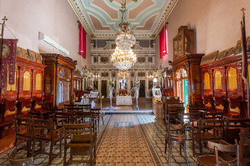 Ornate church interior with wooden pews and a chandelier.