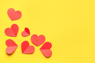 Red paper hearts on yellow background. Valentine's Day celebration