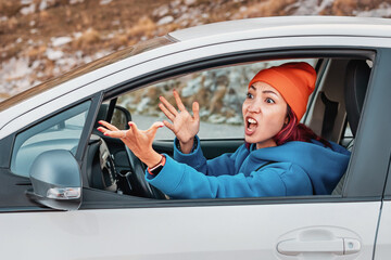 Young woman driving car exhibits road rage, screaming and gesturing angrily
