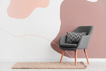 Stylish grey armchair with cushion in modern living room