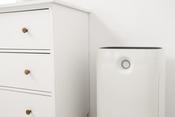 Air purifier near commode in light bedroom