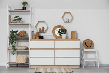 Interior of light living room with commode, shelf unit and stool