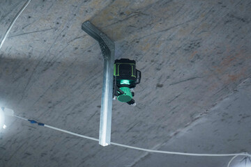 Laser level with green beams. Indoor construction work. Bottom view.
