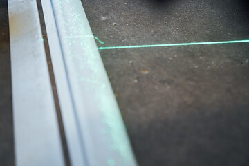 In the center of the room, two green laser lines merge on the concrete floor, marking an exact...