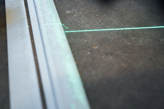 In the center of the room, two green laser lines merge on the concrete floor, marking an exact reference for installation.