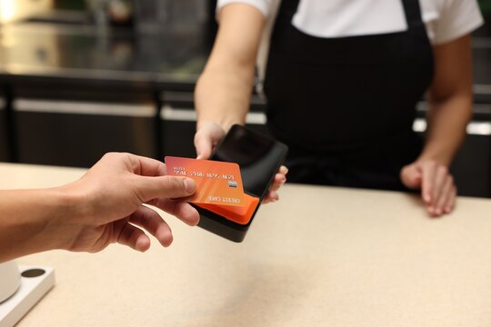 Man paying with credit card via terminal in cafe, closeup