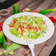 Fresh Lettuce and Tomato Salad on a White Plate with Rustic Background

