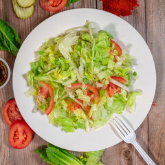 Fresh Lettuce and Tomato Salad on a White Plate with Rustic Background

