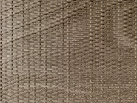 Dark greyish fawn synthetic resin or polypropylene knitted braided rattan wicker for sofas, armchairs, tables, garden furniture, porch, terrace, patio, pool, outdoor texture or background.