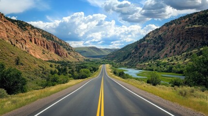 Naklejka premium An expansive road cutting through the Rockies, crystal-clear river running parallel