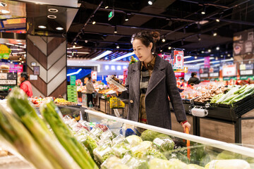 A Woman Selecting Fresh Produce in a Vibrant Supermarket Environment