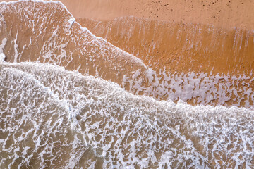 Serene Aerial View of Waves Gently Crashing on Sandy Beach