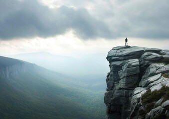 Fototapeta premium A solitary figure silhouette stands atop a rocky mountain.