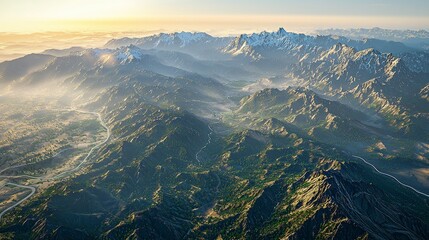 Majestic sunrise over a vast, mountainous landscape with winding roads and snow-capped peaks.
