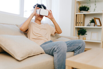 young man using virtual reality headset, sitting on a couch in a bright living room with soft furnishings, creating a modern and tech savvy atmosphere for immersive experiences