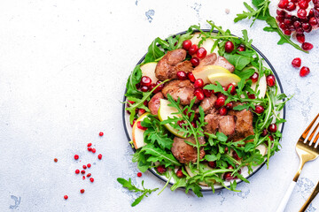 Salad rich in vitamins and minerals with chicken liver, apple, pomegranate and arugula. White background, top view