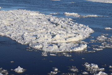 A water stream of a river with icebergs. Pieces of ice on the water. Blue and white background and the St-Laurent river. in winter. A water background in winter. 