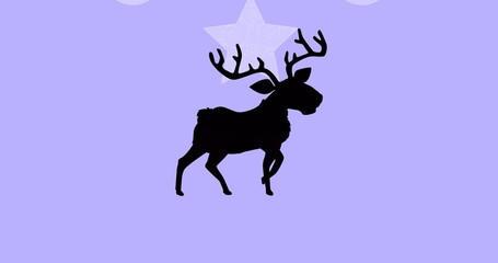 Black silhouette of reindeer walking against christmas hanging decorations against purple background