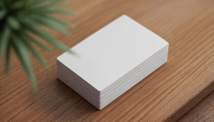 Stack of blank business cards on a wooden table with a plant for branding and marketing concepts