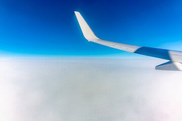 View from the airplane window at a beautiful cloudy sky and the airplane wing