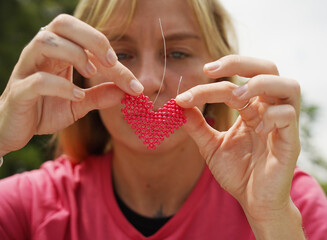 Young woman beading colorful bracelets outdoors in a park