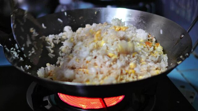 Video footage of a chef making fried rice with eggs for lunch in a home kitchen.