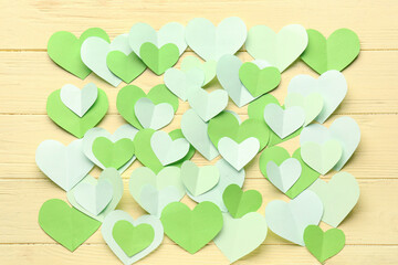 Fototapeta premium Green paper hearts on yellow wooden background. Valentine's Day celebration
