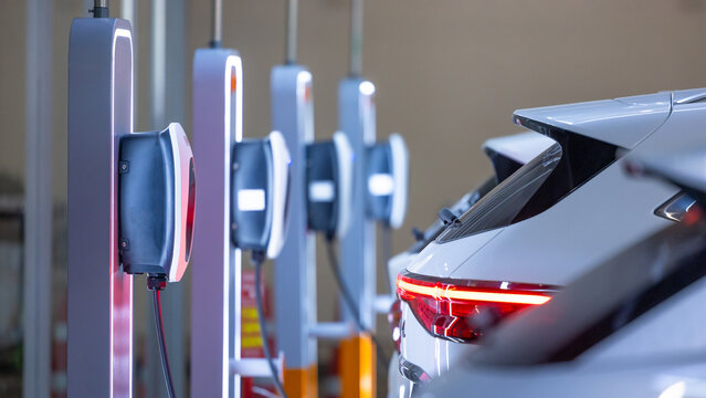 EV charger and electric car, Electric car charger station for charge ev battery, Plug for vehicle with electric engine, EV charger clean energy, Charging point at car parking lot department store.