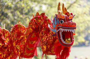 A large red dragon with gold accents is displayed in a park
