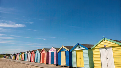 Naklejka premium Colorful beach huts lining a sunny shoreline