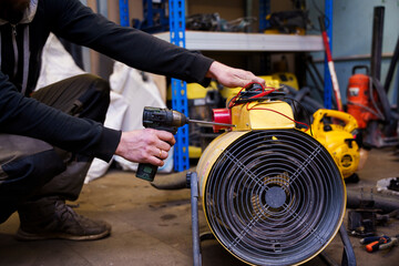 a male repairman repairs industrial electric heaters, he has a tool and a multimeter in his hands