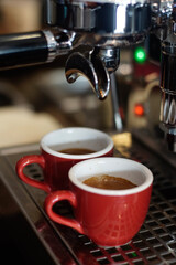 Two red cups on espresso machine