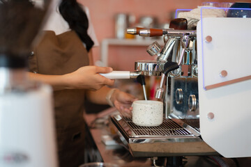 Young barista making coffee, coffee preparation service concept.