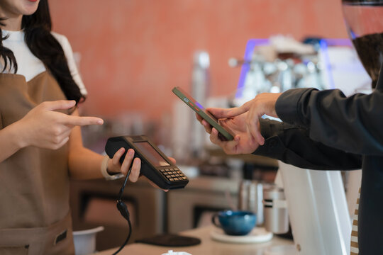 Closeup shot of cashier hands. Seller using touch smartphone for accepting client customer payment. Small business of coffee shop.