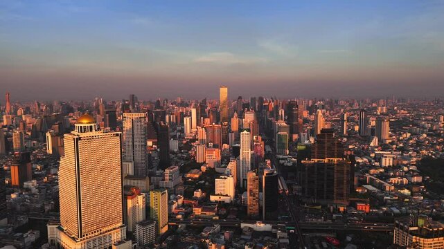 Bangkok high aerial view from the Chao Phraya River to Bang Rak and Si Lom districts at sunset. A large asian capital city with skyscrapers and millions of inhabitants. Cinematic 4k footage