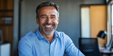 Obraz premium Business portrait featuring a happy businessman in an office setting. This confident entrepreneur, a mid aged man, smiles while looking at the camera, showcasing professionalism and positivity.