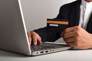 Hand holding credit card and using laptop. Businessman or entrepreneur working from home. Online shopping, e-commerce, internet banking, payment, spending money, work from home concept.