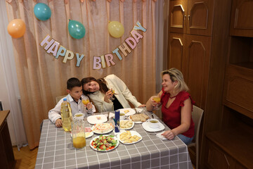 Celebrating the boy's birthday, the guests sit down at the table, drink and treat themselves....