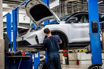 A car mechanic removed a wheel from a SUV on a lift at a car service center for repairs
