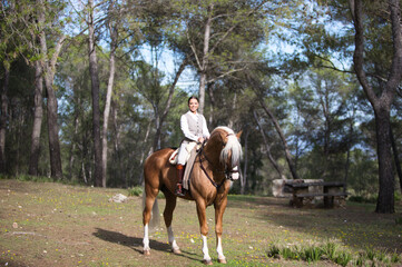 portrait of equestrian woman, young and beautiful, riding and holding the reins of her purebred...