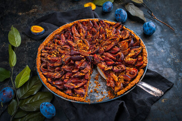Traditional German Zwetschgenkuchen with sliced plums offered as top view on a rustic backing sheet