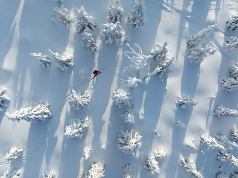 Aerial view of ski touring man crossing winter mountains, fresh snow.